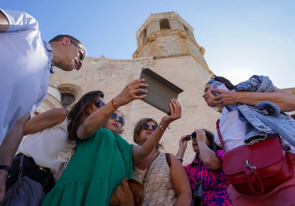 Grup de persones consultant una tauleta durant una visita guiada a un edifici històric de Sitges
