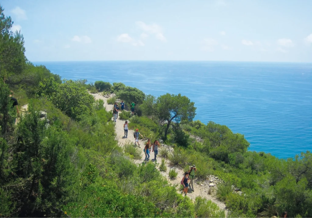 Senderistes caminant per un sender costaner amb vistes al mar Mediterrani blau a Sitges